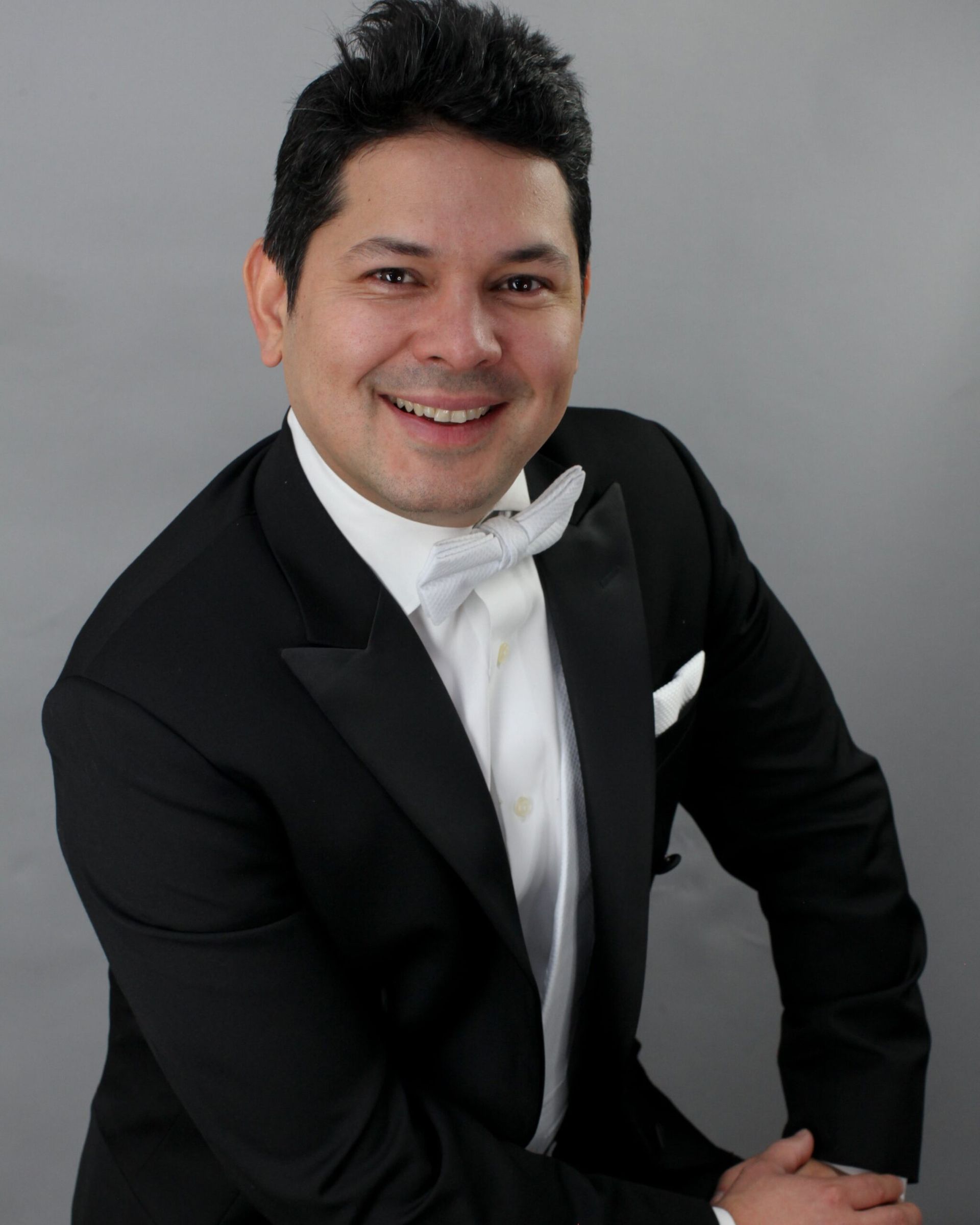 A man in a tuxedo and bow tie smiles for the camera