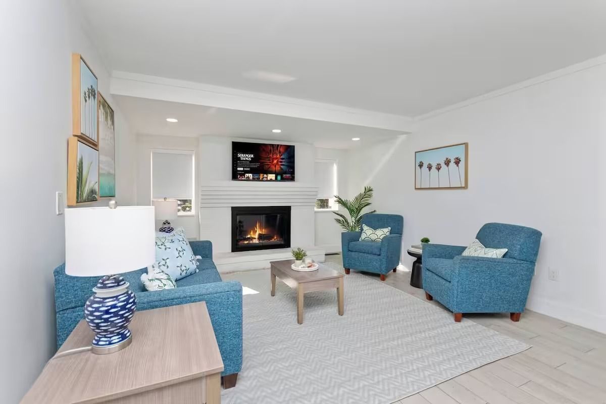 Living room with fireplace, blue sofa, armchairs, and wood coffee table.
