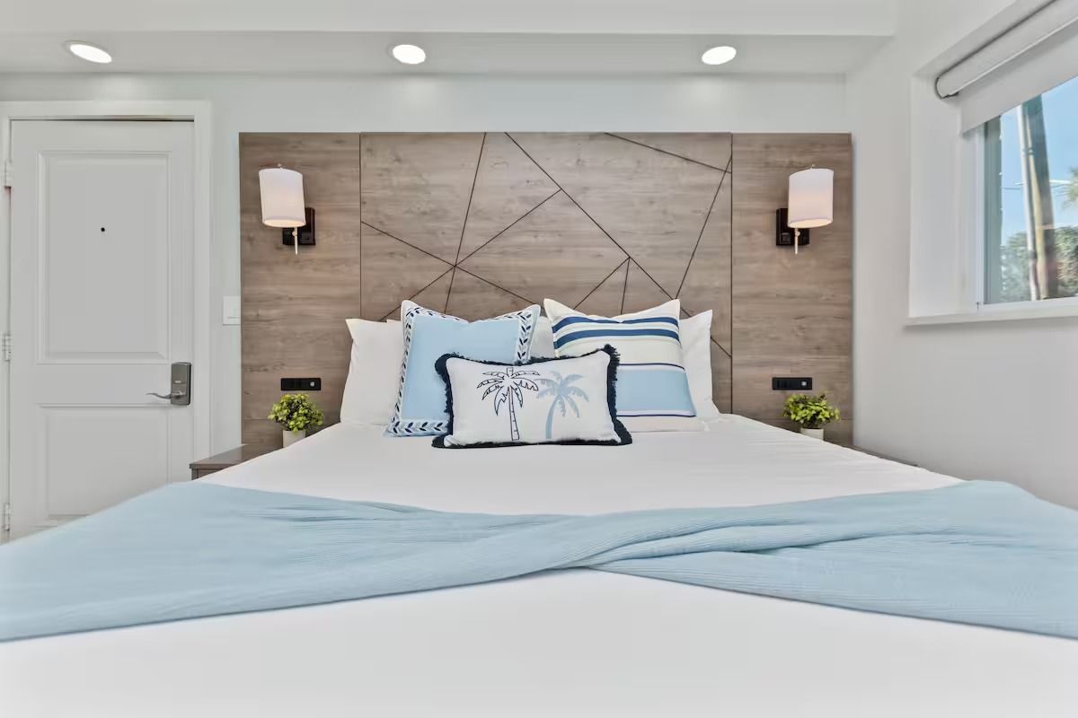Bedroom with a king-sized bed, decorative pillows, light blue throw, and geometric headboard.