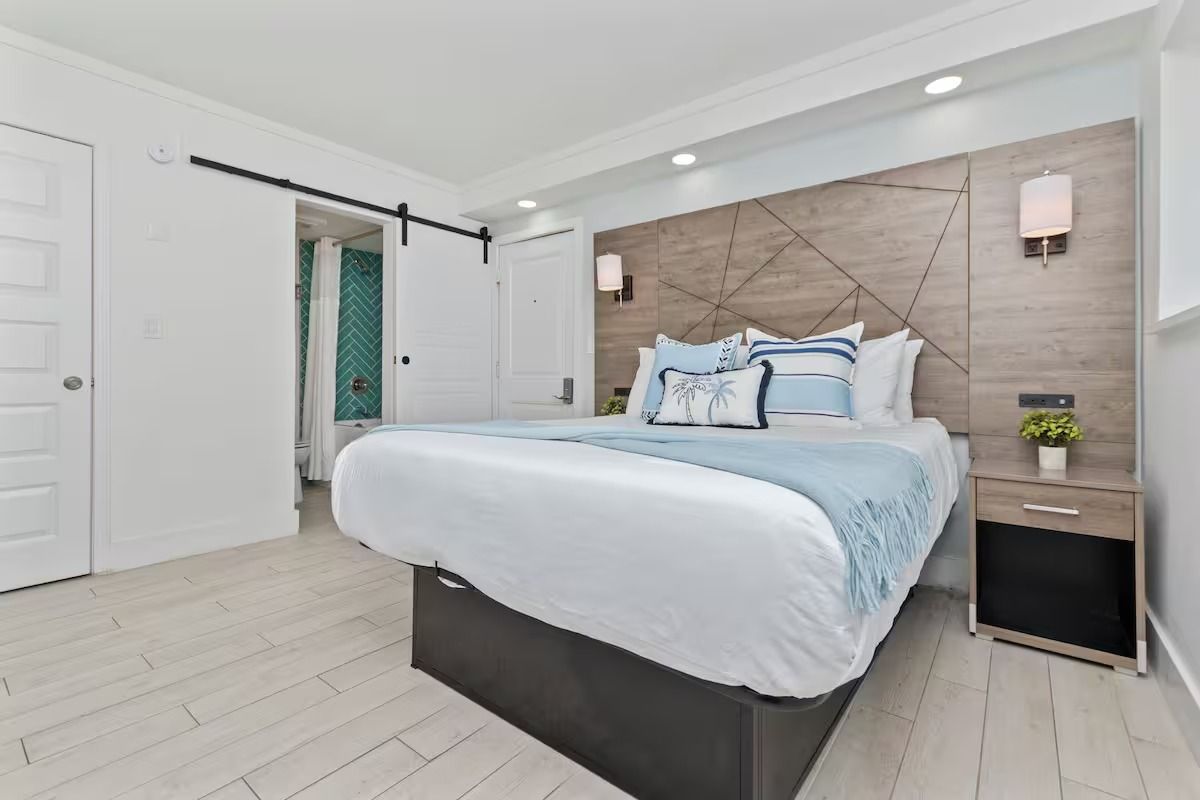Bedroom with a bed, nightstand, and sliding door to a bathroom. Light blue and white decor.