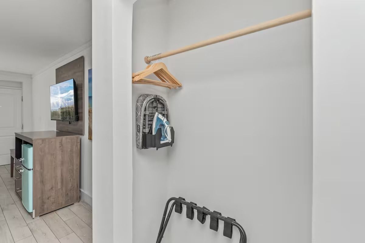 Closet with a hanging rod, hanger, backpack, and luggage rack in a hotel room.