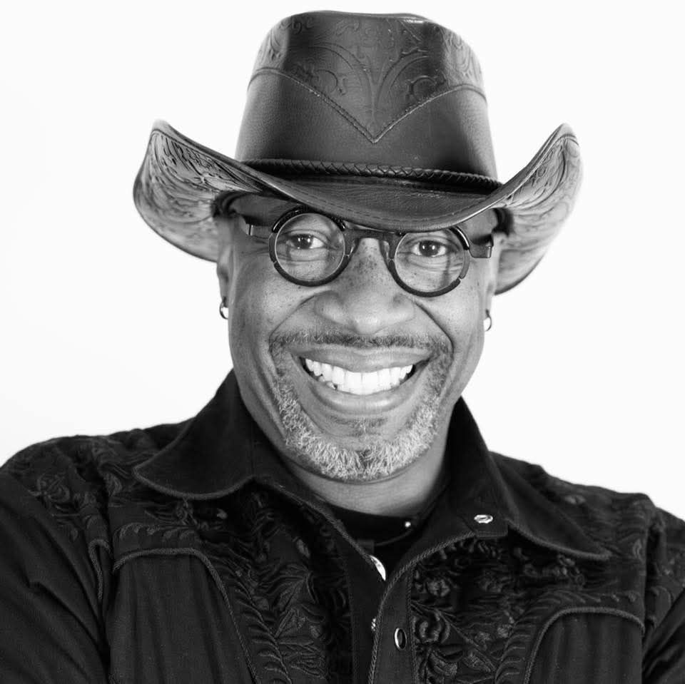 A black and white photo of a man wearing a cowboy hat and glasses