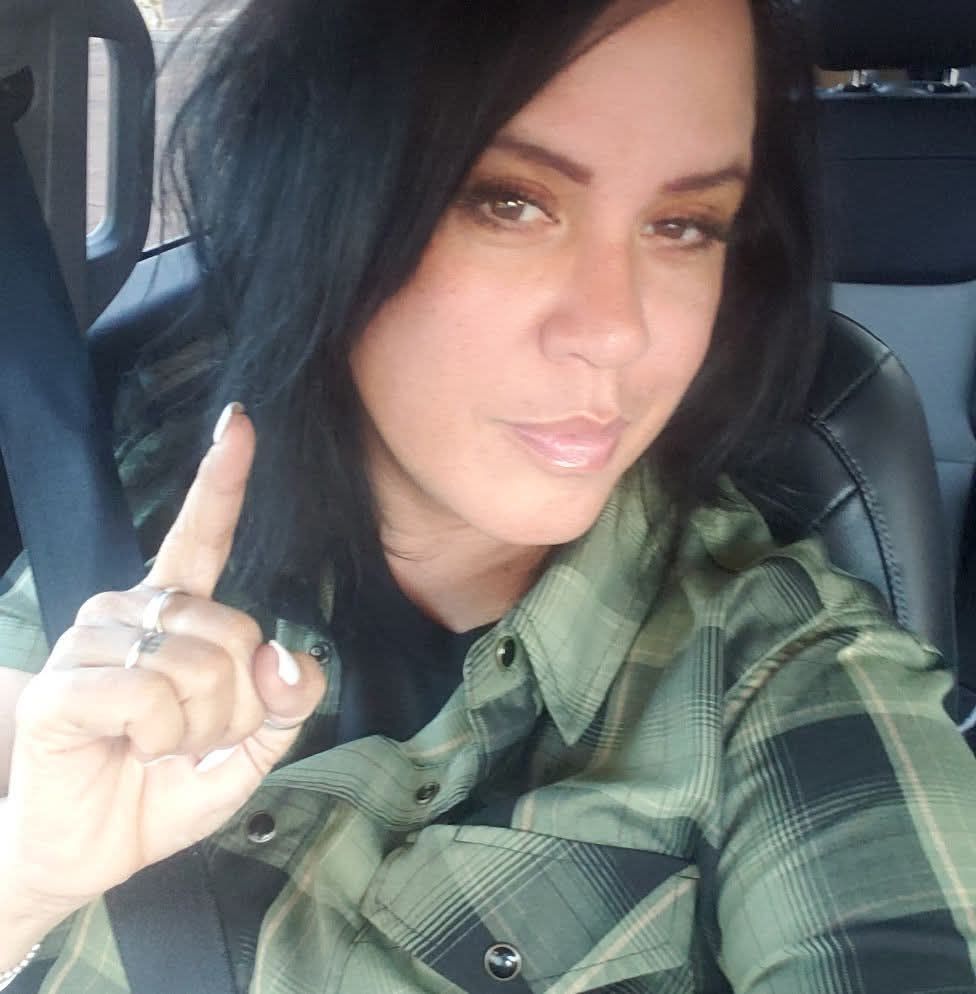 A red heart with a cross inside of it and two hands holding it.