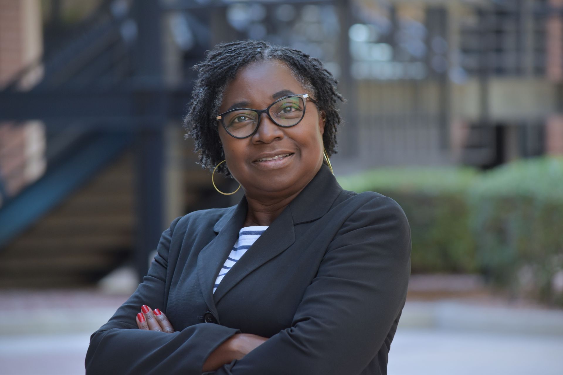 A woman wearing a headband and hoop earrings smiles for the camera