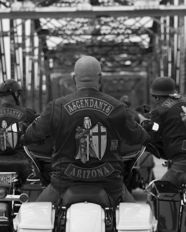 A group of men are riding motorcycles in a black and white photo.