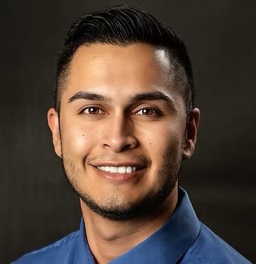 A man in a blue shirt is smiling for the camera.