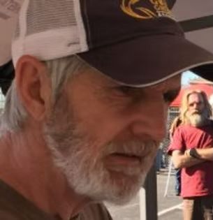 A man with a beard is wearing a baseball cap.