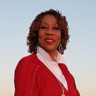 A woman in a red jacket and white shirt is smiling for the camera.