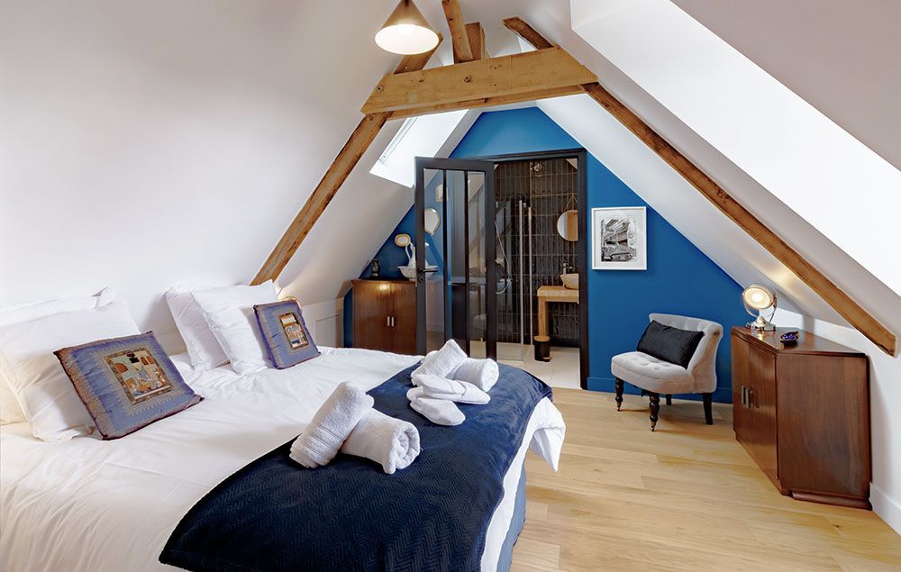 Chambre avec lit, mur d'accent bleu et entrée de salle de bain par des portes vitrées.
