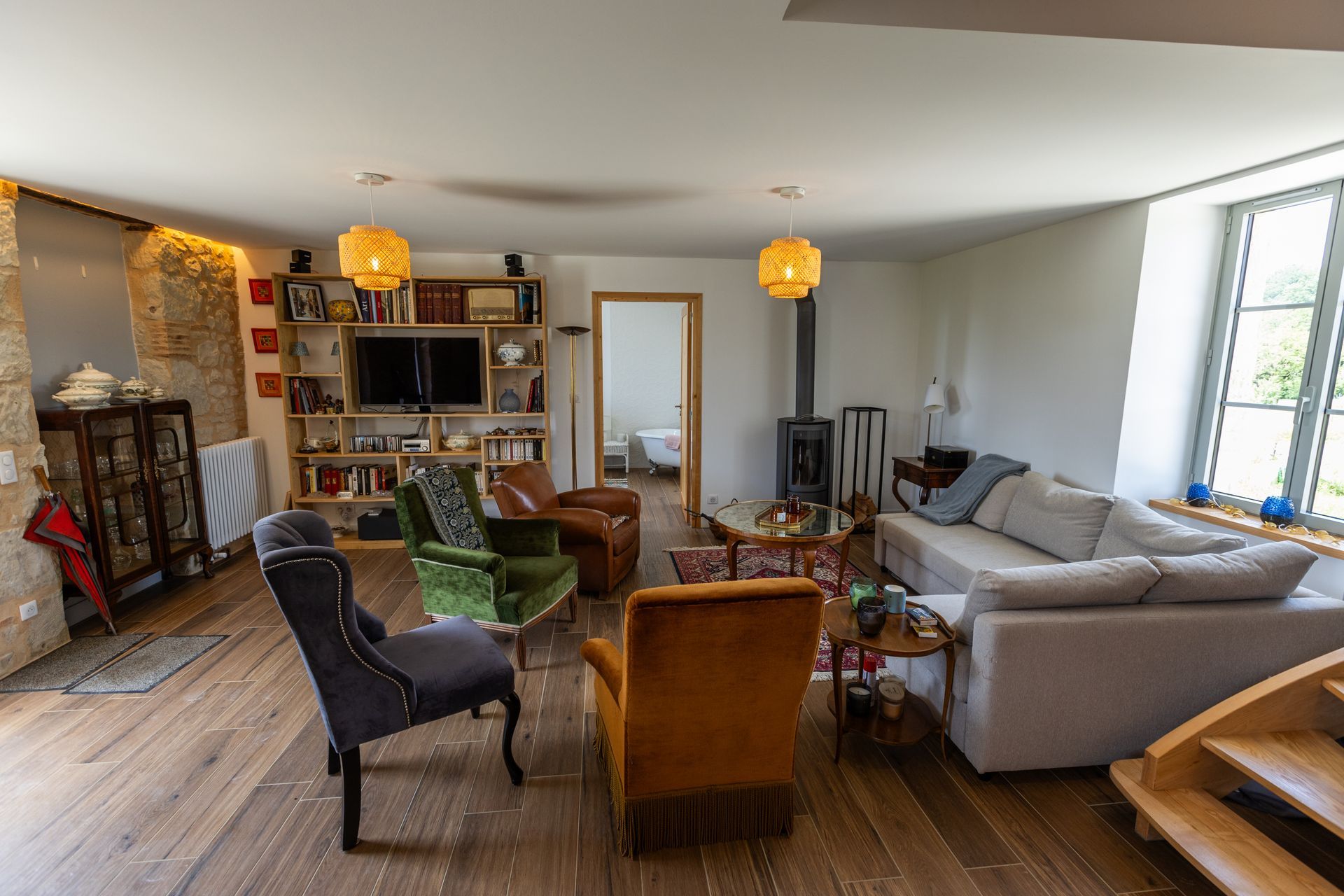 Séjour avec parquet, divers sièges, étagères et cheminée.