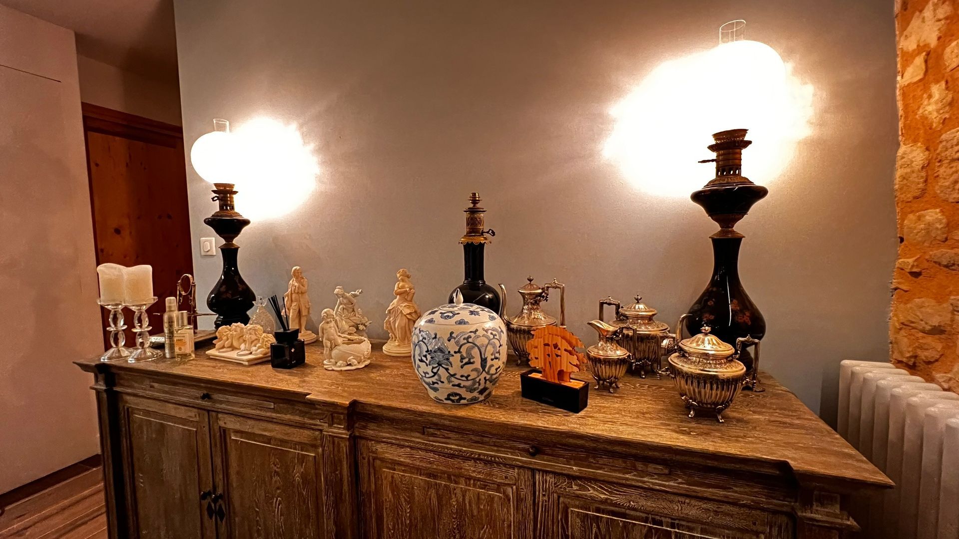 Une armoire en bois avec des objets décoratifs, notamment des lampes et des vases, contre un mur bleu.