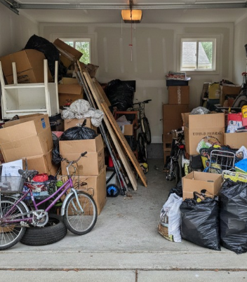 Person pointing at document, speaking with another over a counter in a room, with a tv in the background.
