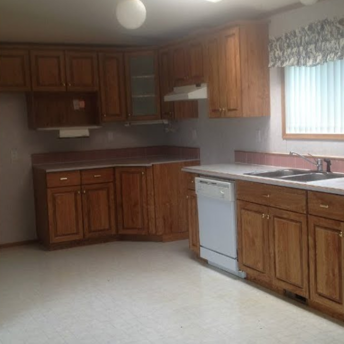 Kitchen with wooden cabinets, white appliances, and a window with blinds.