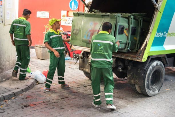 Workers in blue shirts and masks cleaning a glass railing on an elevated walkway, with a bucket nearby.