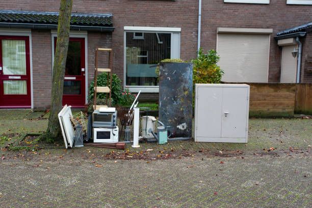 People picking up trash in a grassy field, placing it into black bags.
