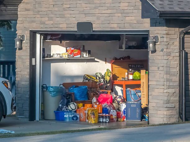 Open garage filled with clutter; a mix of boxes, bags, and various items on shelves. Exterior stone wall.