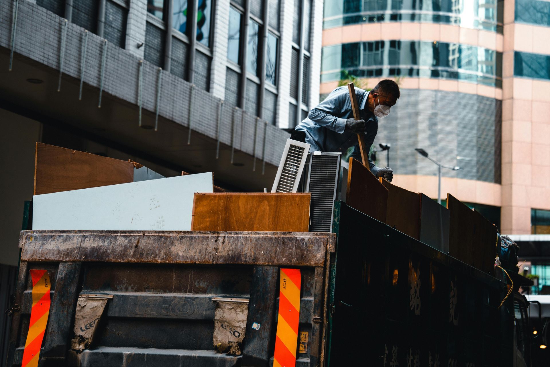 Man in mask loads a truck with furniture in an urban setting.