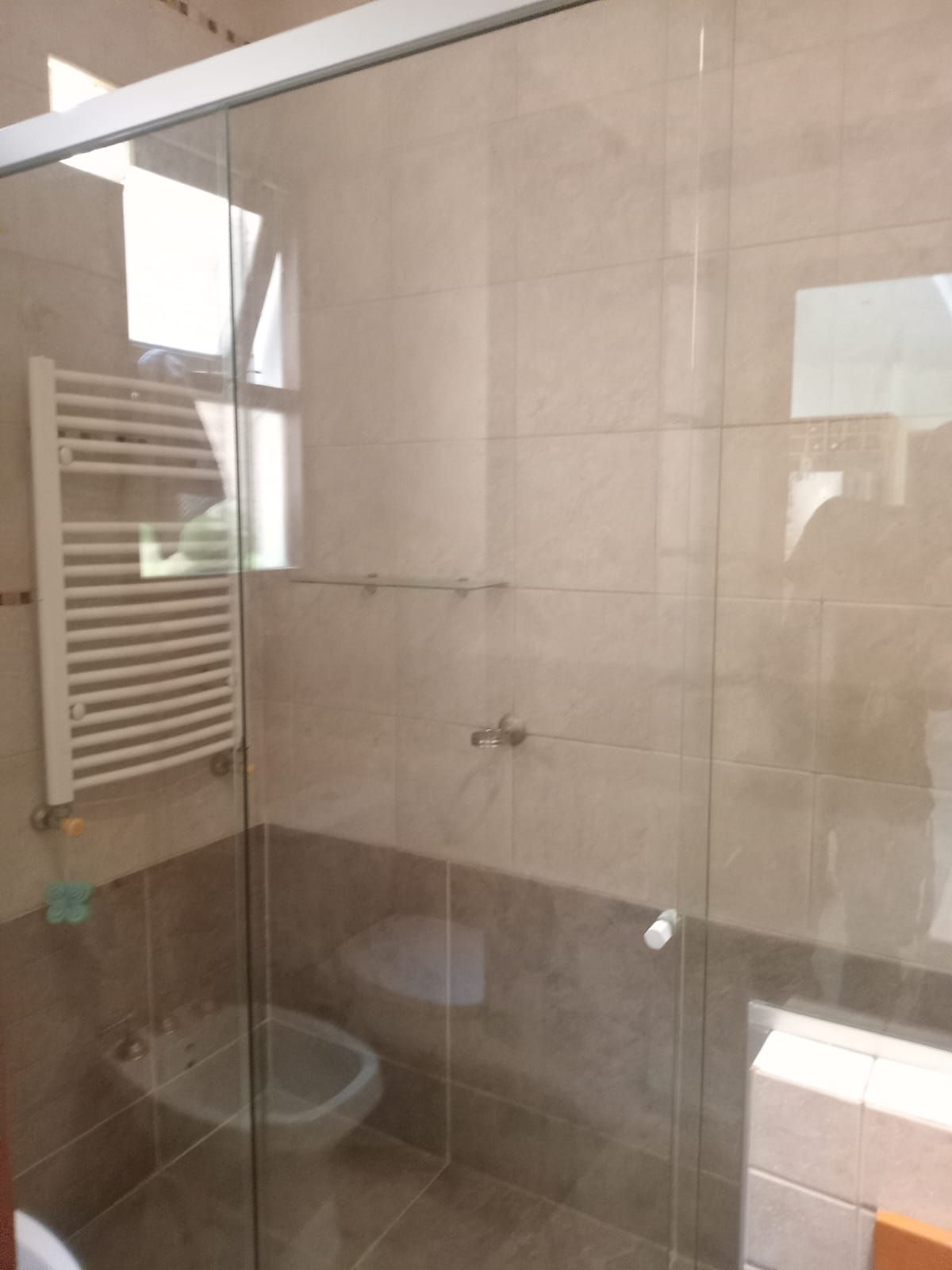 Baño con puerta de ducha de cristal, paredes alicatadas, calentador de toallas y bidet.