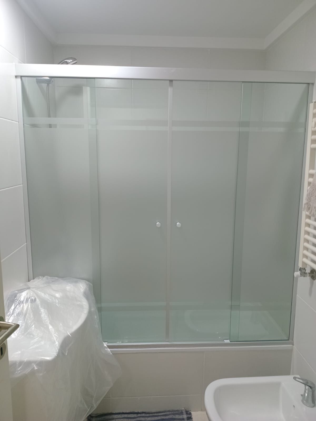 Baño con bañera y puertas de ducha corredizas de vidrio esmerilado.