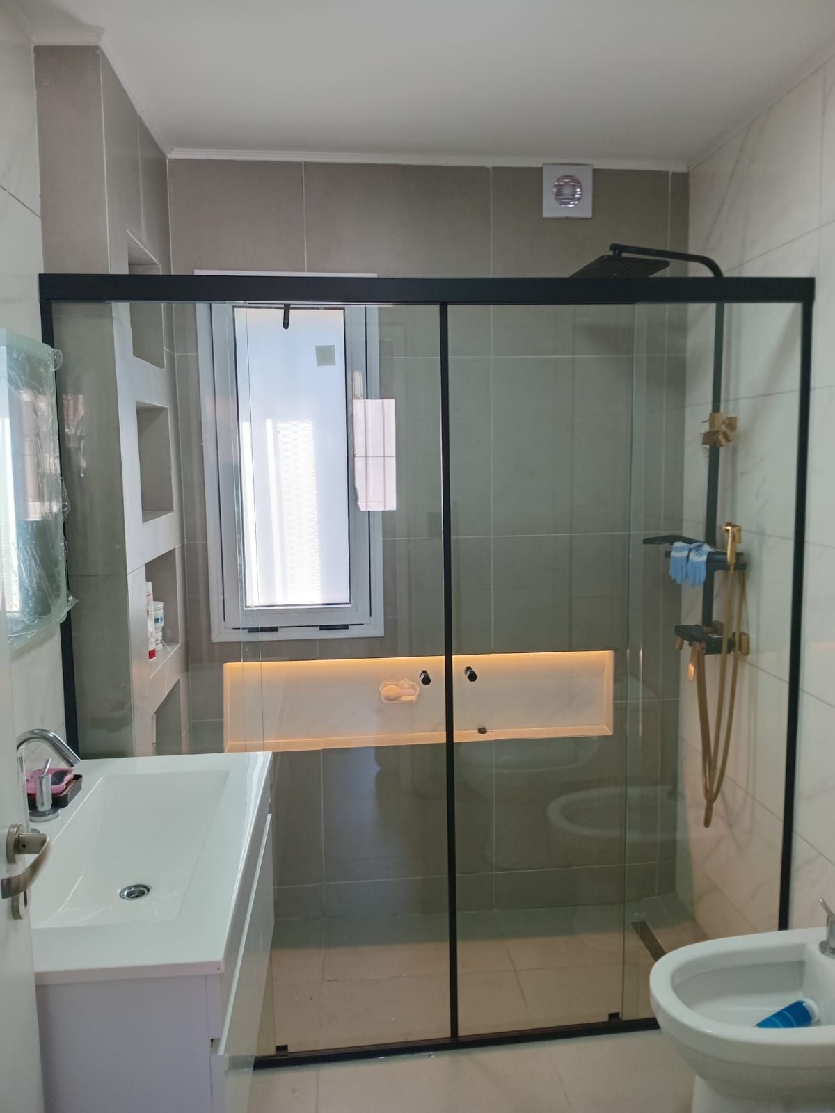 Baño moderno con ducha de cristal, inodoro y lavabo.