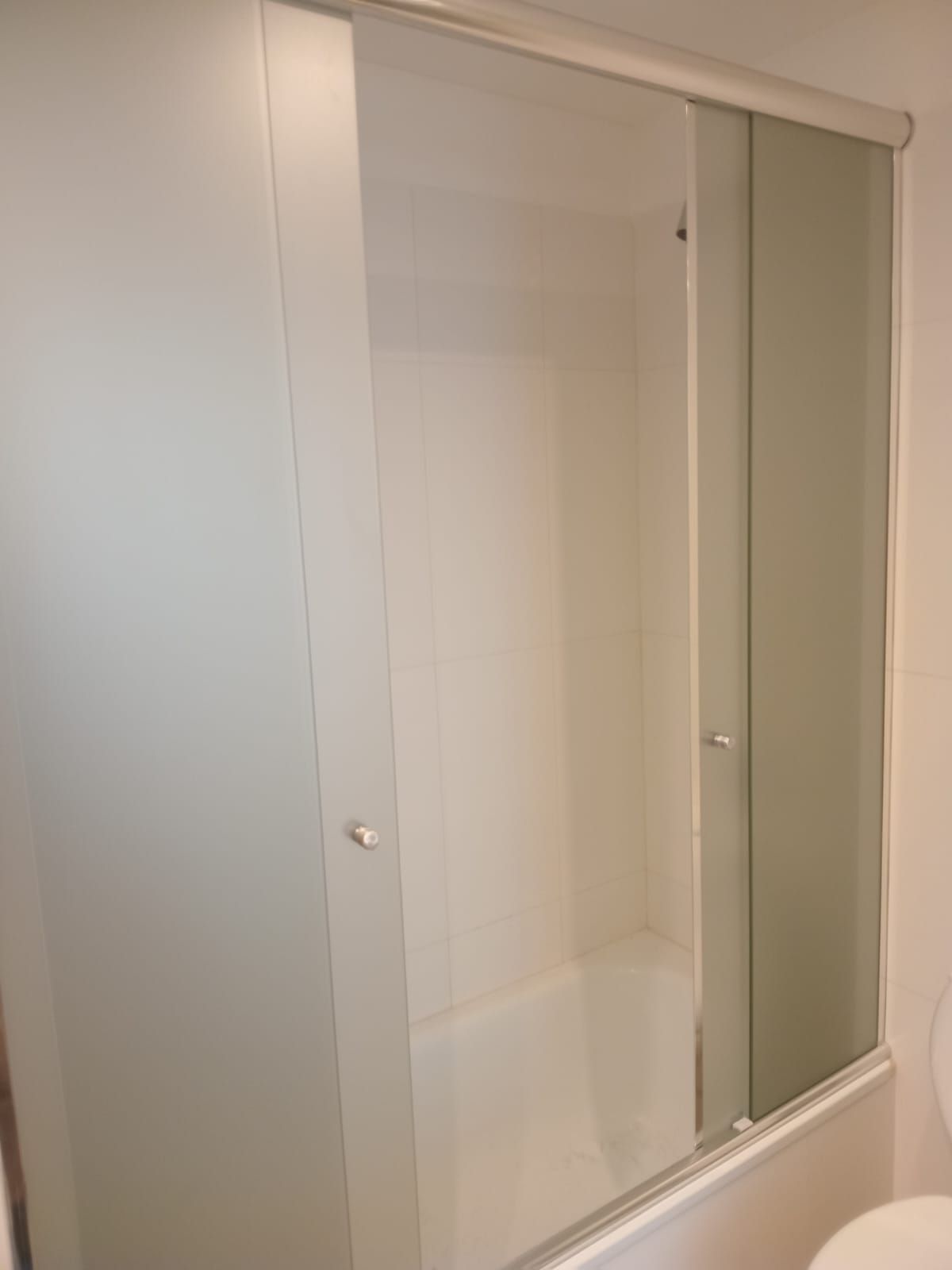 Mampara de ducha blanca con puertas correderas de cristal.