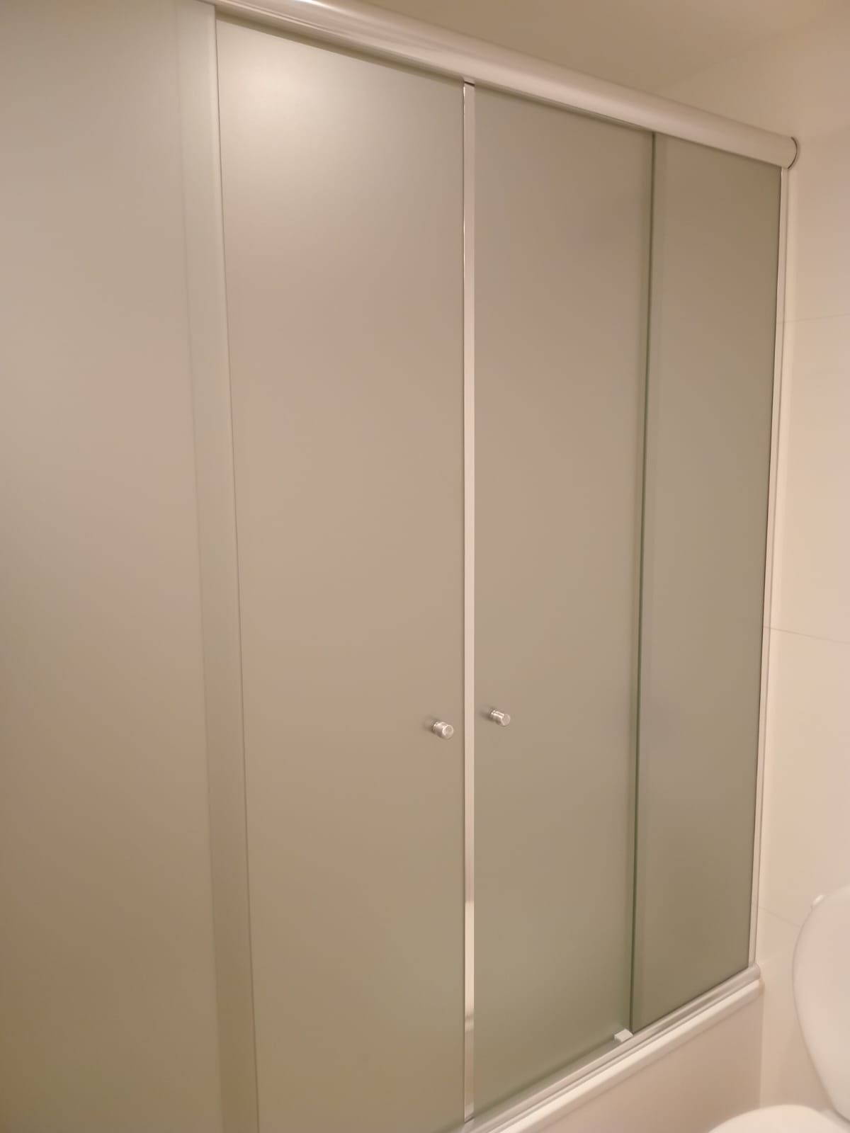 Puertas corredizas de armario cerradas, paneles gris claro, molduras blancas, en una habitación.