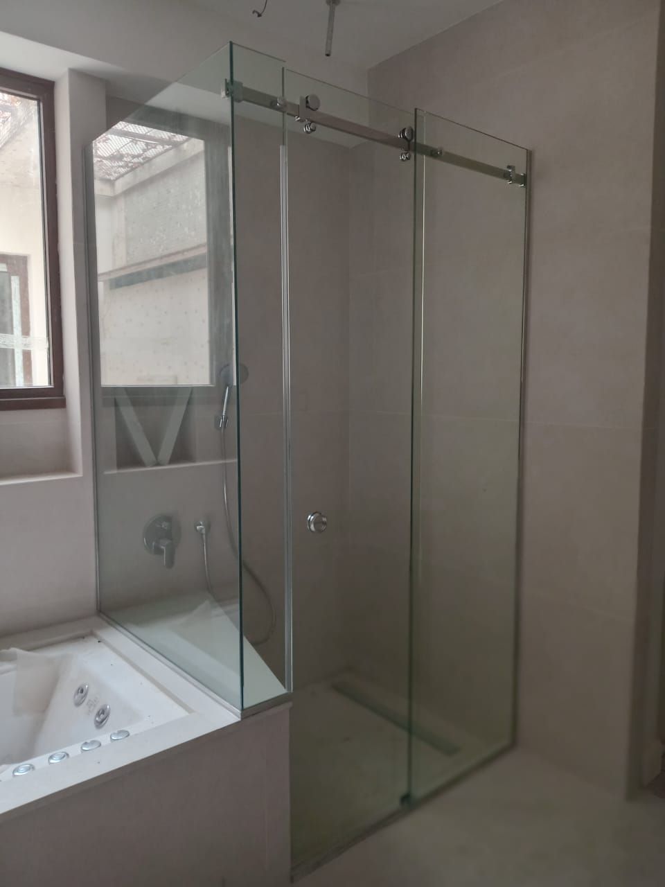 Mampara de ducha de cristal con puerta corredera en baño.