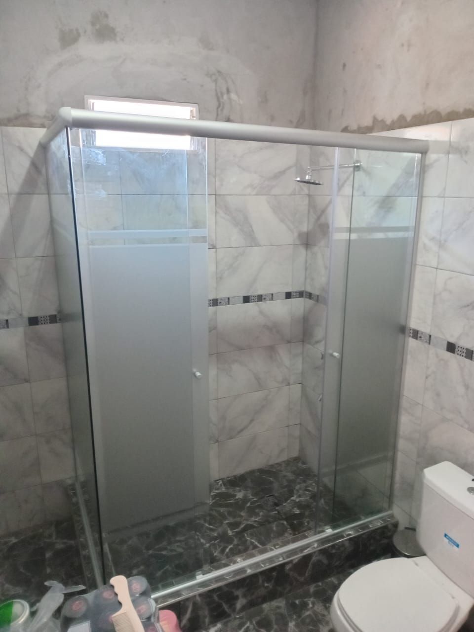 Mampara de ducha de cristal en baño con puertas de cristal parcialmente esmerilado.