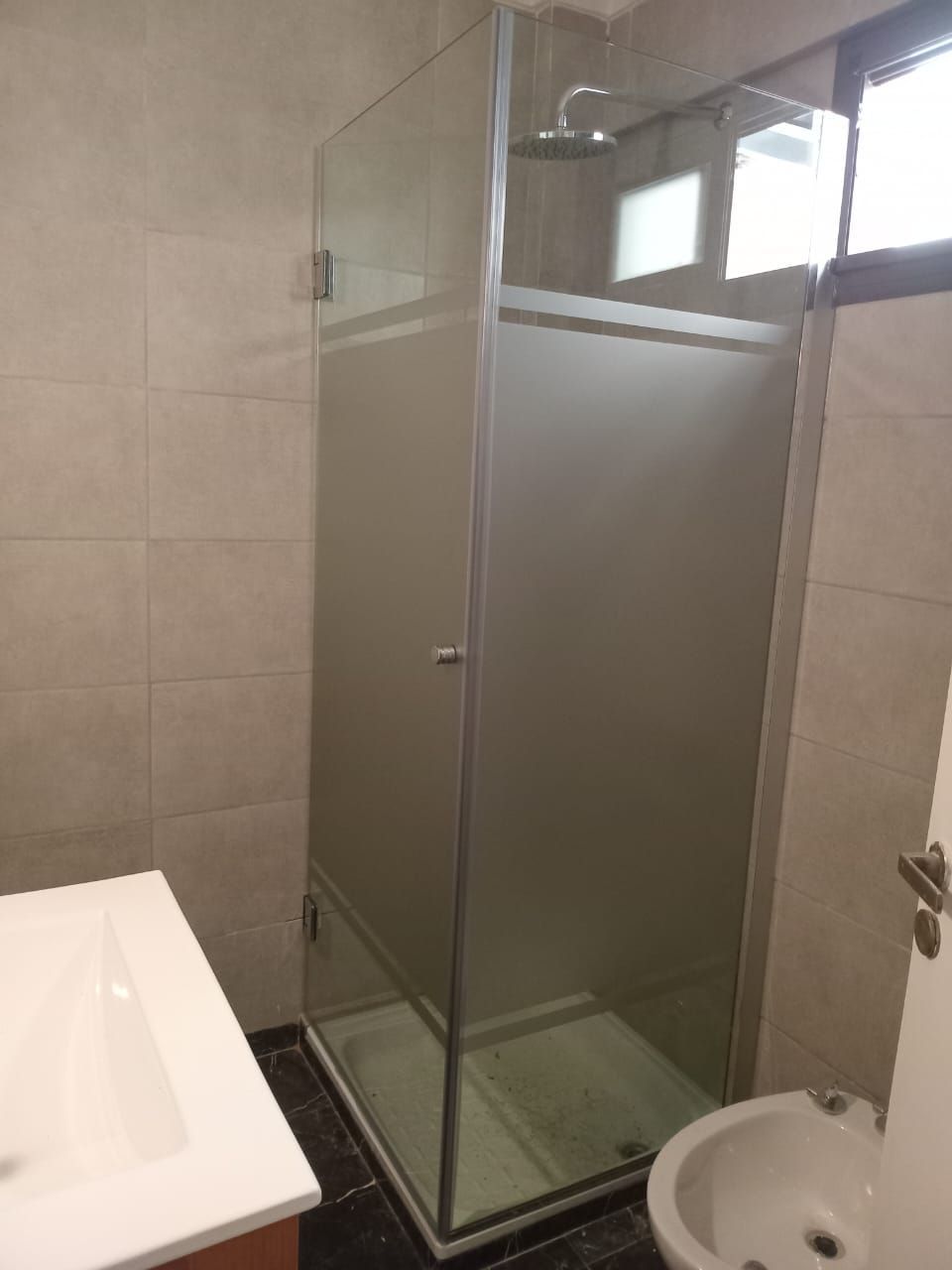 Cabina de ducha con puerta de cristal esmerilado en un baño moderno.
