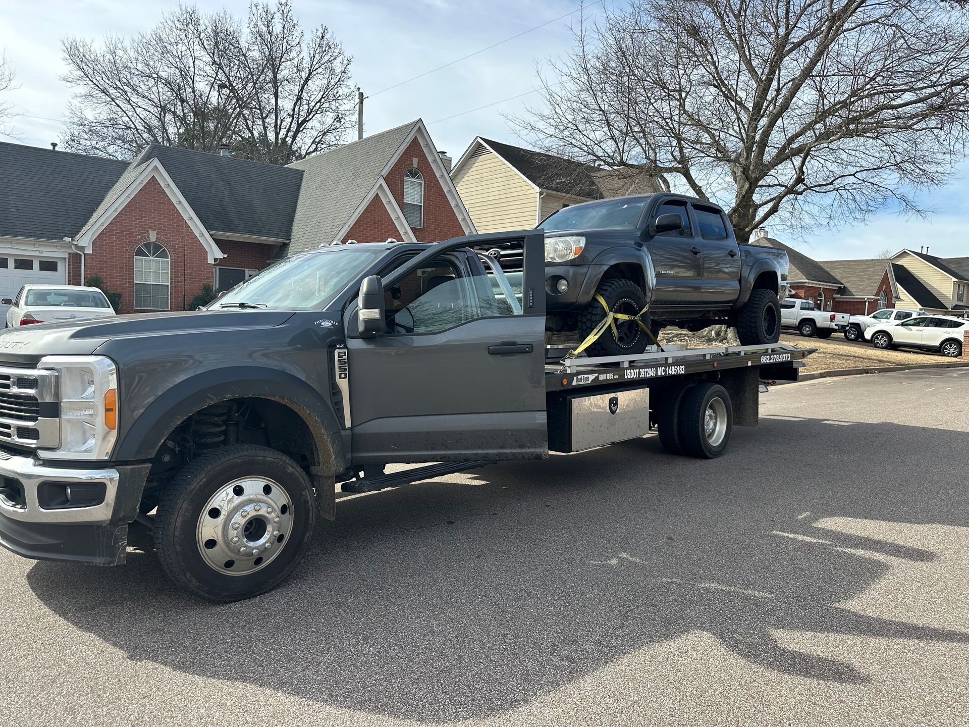 A tow truck is carrying a car on the back of it.