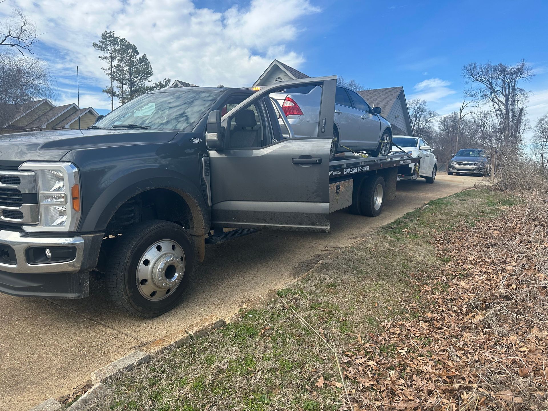 A tow truck is towing a car down a dirt road.