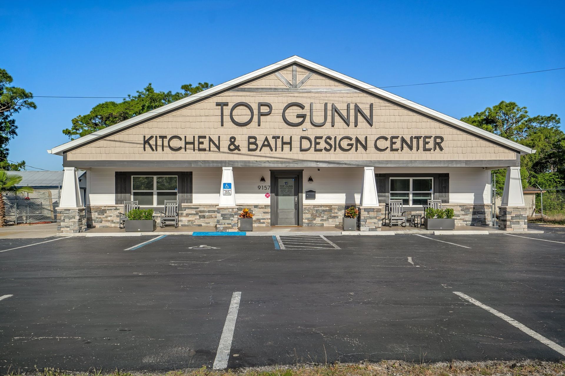 Exterior of Top Gunn Kitchen & Bath Design Center: tan building with black text, blue sky, empty parking lot.