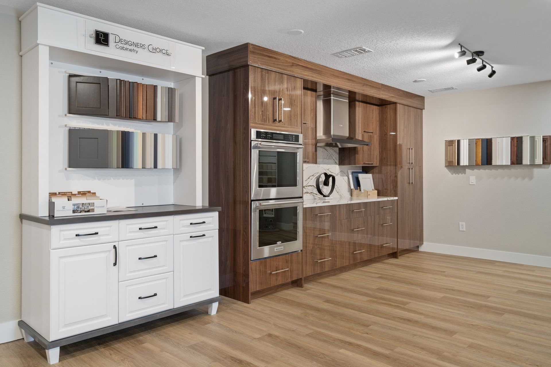Kitchen showroom with cabinetry displays and sample swatches on a light wood floor.