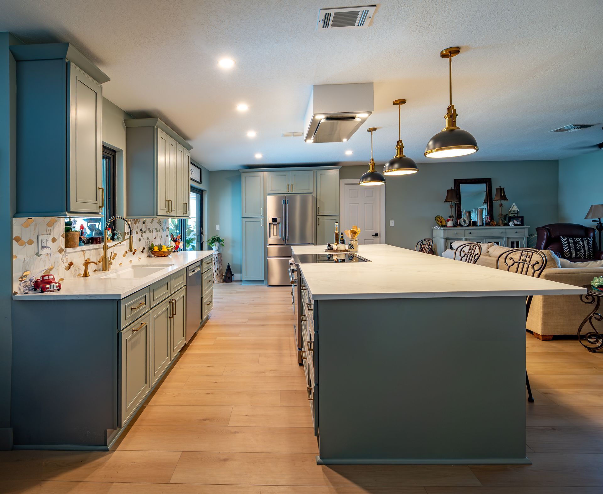 Spacious kitchen with blue-gray cabinets, a large island, stainless steel appliances, and light wood floors.