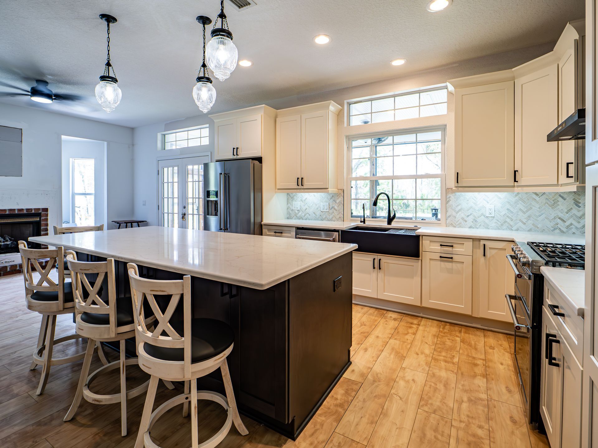 Modern kitchen with white and dark cabinets, island, and wooden floors.