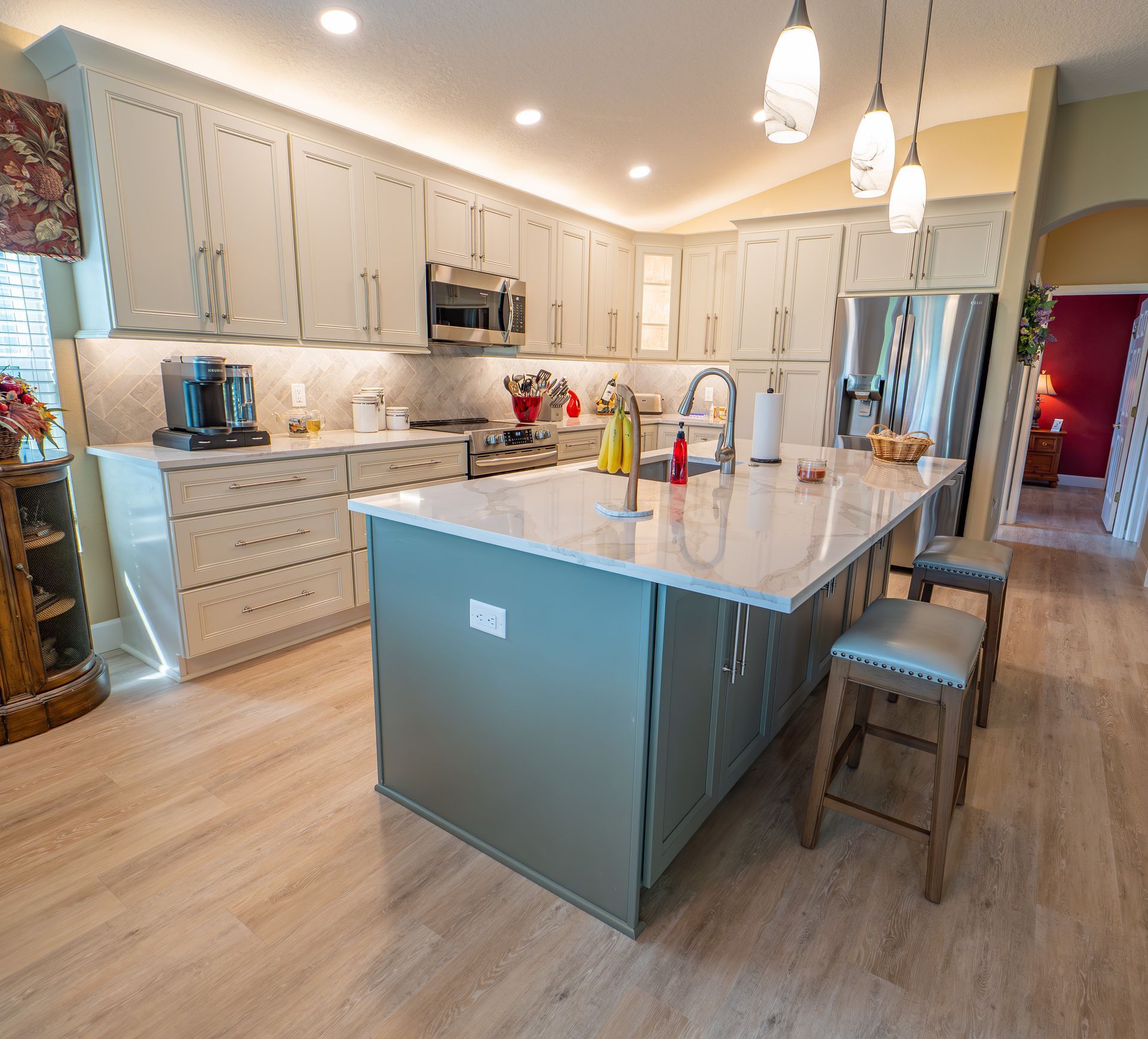 Modern kitchen with light blue cabinets, island, and stainless steel appliances.