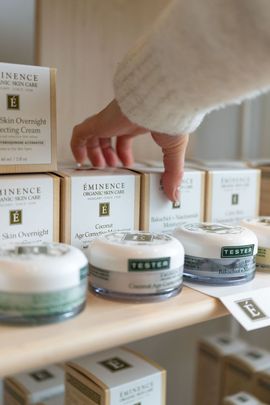 Hand reaching for a jar of cream on a shelf with boxed skincare products