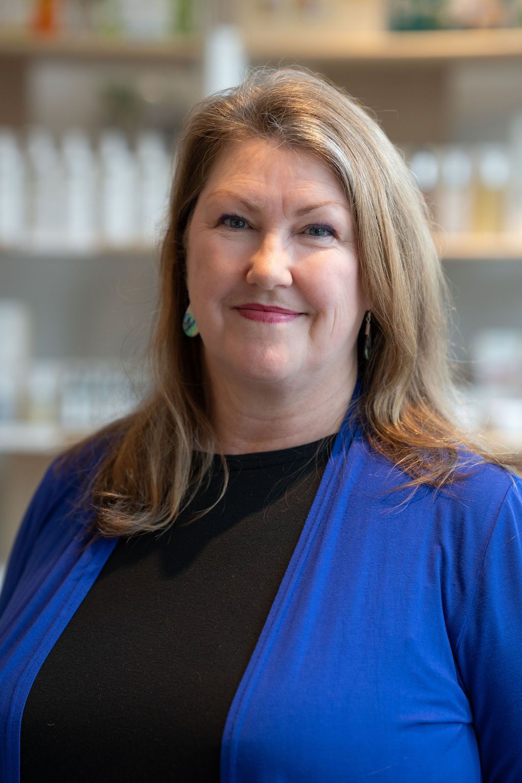 Portrait of a smiling woman in a blue cardigan against a softly blurred indoor background