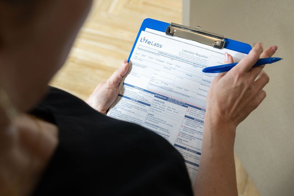 Person holding a clipboard and pen, filling out a form indoors.