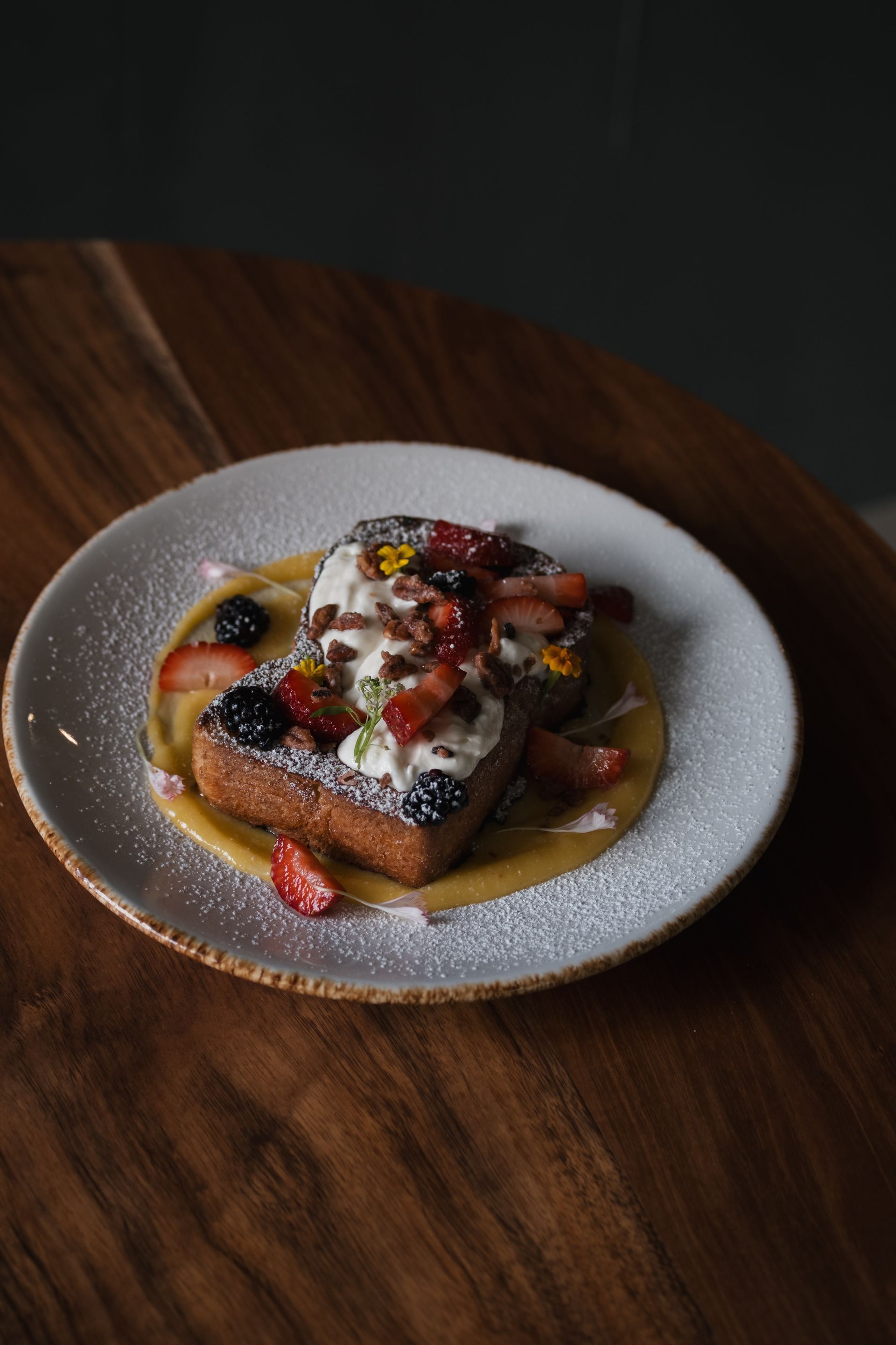 French toast topped with berries and whipped cream on a plate with powdered sugar.