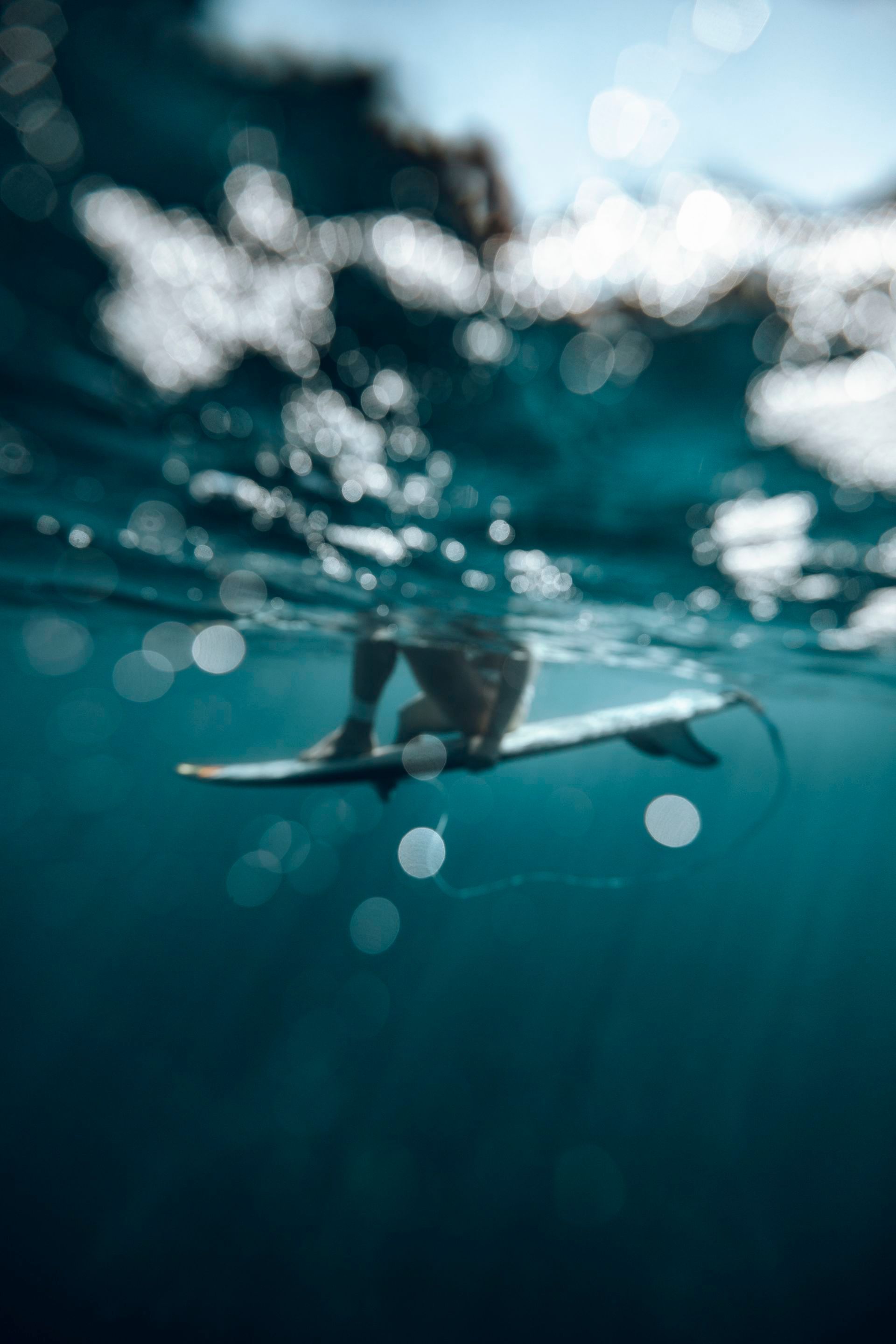 Surfer riding a wave in the ocean. Pale blue water and sky.