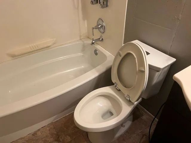 A bathroom with a toilet , bathtub and sink