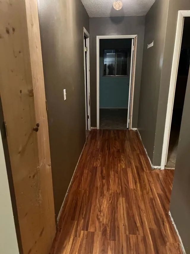 A hallway with hardwood floors and gray walls in a house.