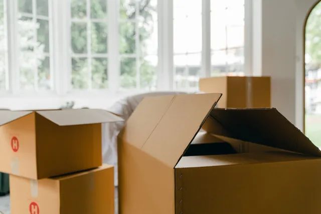 A bunch of cardboard boxes are stacked on top of each other in a living room.