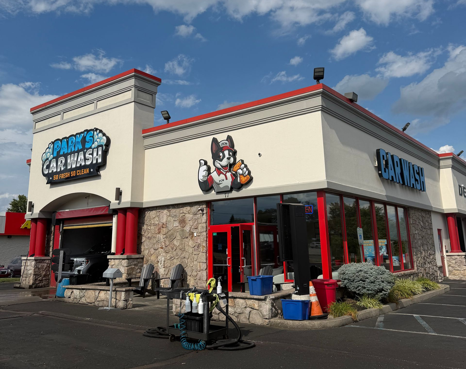 A red car is going through a car wash with red and blue brushes.