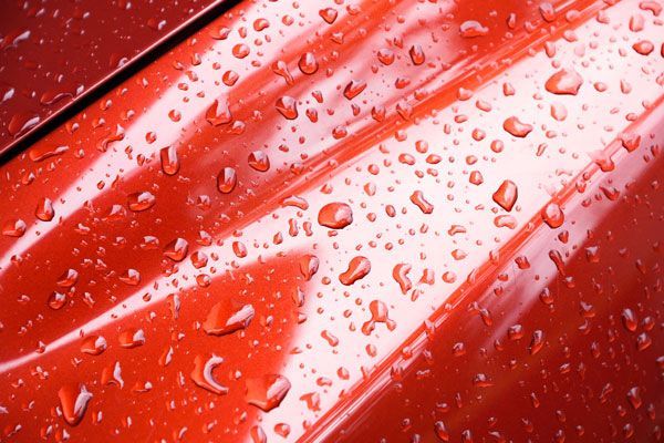 a close up of a red car with water drops on it