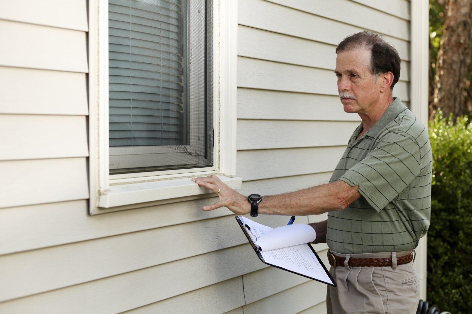 Senior adult male inspects an exterior window - Decatur, AL - Home Inspection Pros