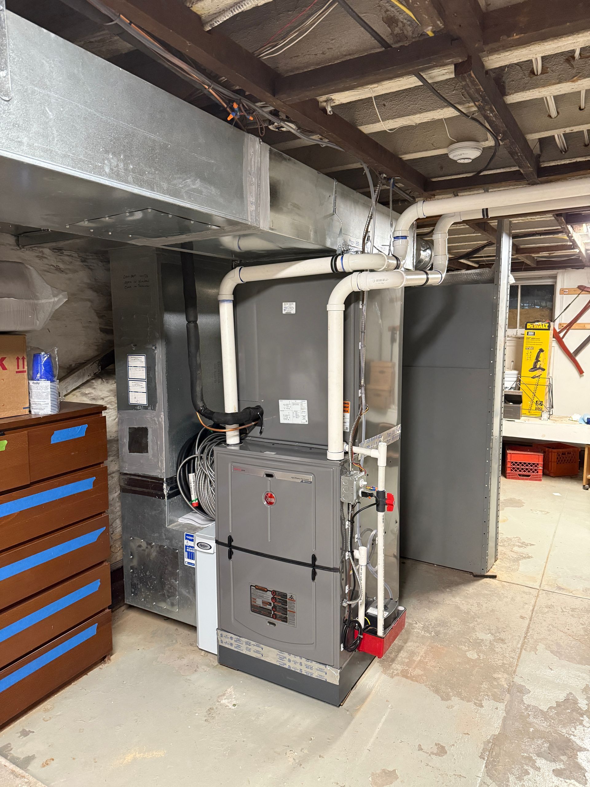 Air conditioning units lined up outdoors next to a building and greenery.
