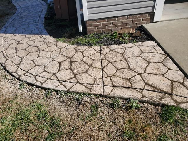 A stone walkway leading to a house with a brick building in the background.