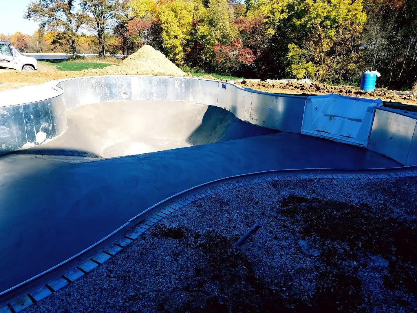 A large swimming pool is being built in a backyard
